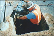 Worker Emerging from the Ground to Grab a Pipe